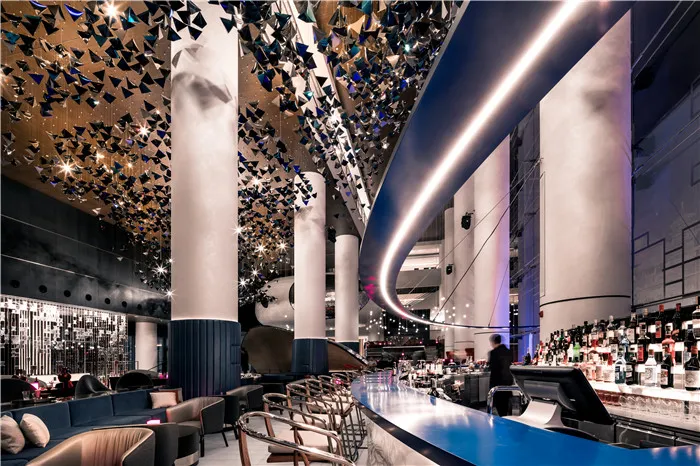 A modern bar interior with metallic decor, glass elements, and concrete surfaces.