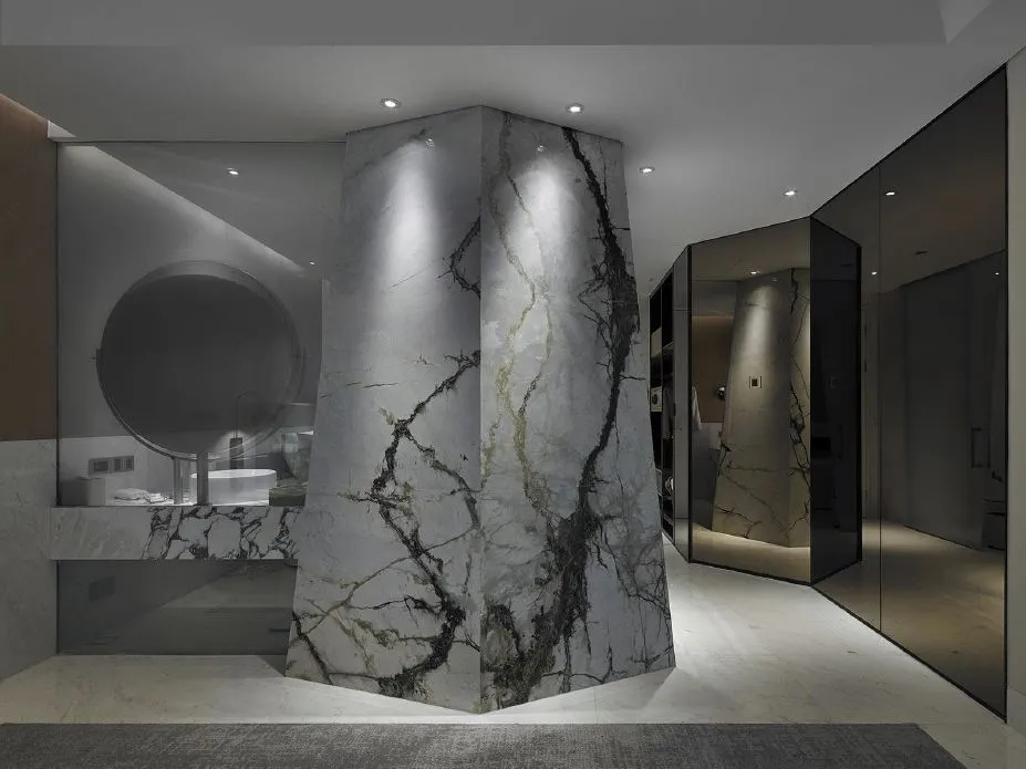 A modern bathroom interior featuring a tall, monolithic marble pillar as a centerpiece.