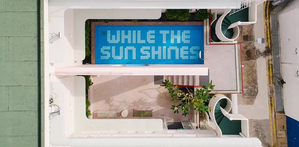 游泳池底部鋪設瓷磚,顯示「While the Sun Shines」字樣。