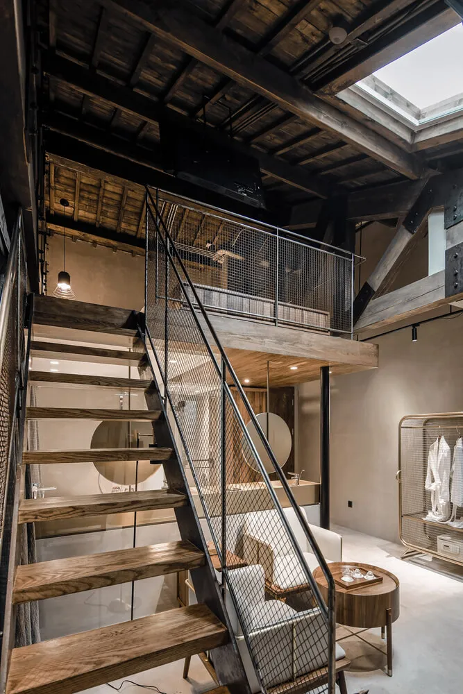 Industrial-style loft interior with metal staircase, concrete walls, and wooden stairs.