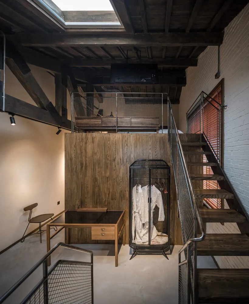 An industrial office space featuring wooden elements, a spiral staircase, and a loft area.
