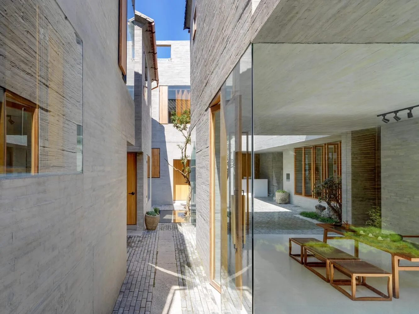 Interior of a minimalist hallway featuring concrete, glass, and wooden elements.
