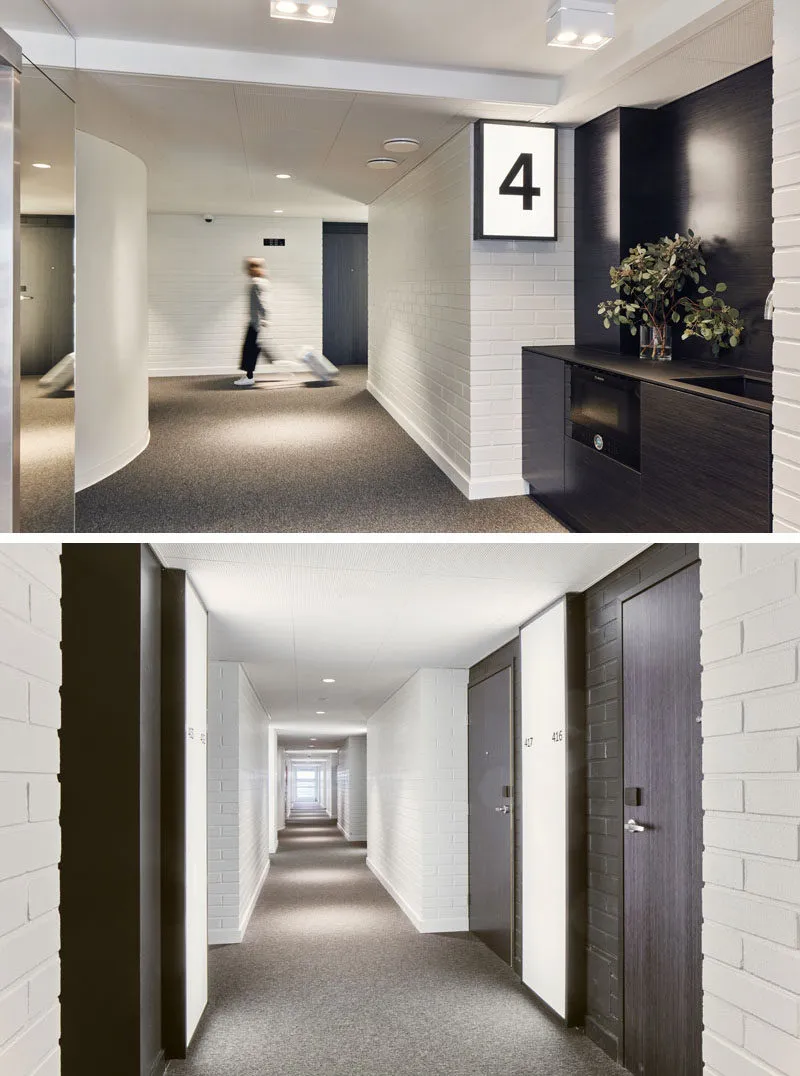 Floor-to-ceiling view of a modern corridor featuring a white brick wall, gray carpeted floor, black doors, and a black kitche