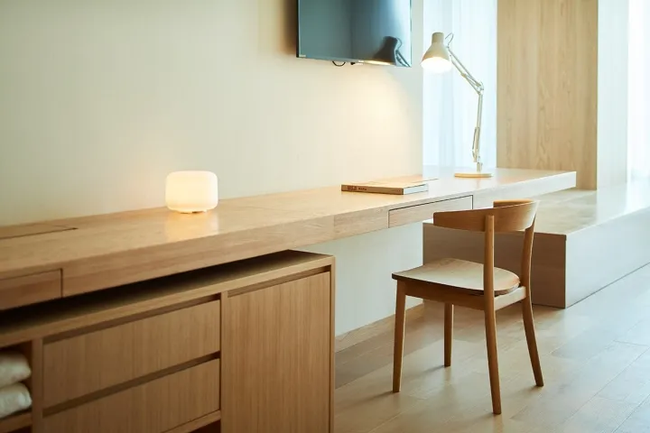 A modern minimalist office space with a wooden desk and chair, minimalistic decor, and ambient lighting.