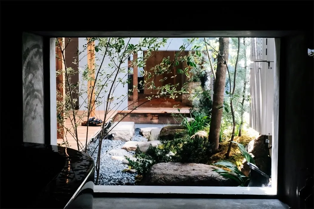 寧靜的極簡花園室內，搭配天然石材、植物與木質平台。