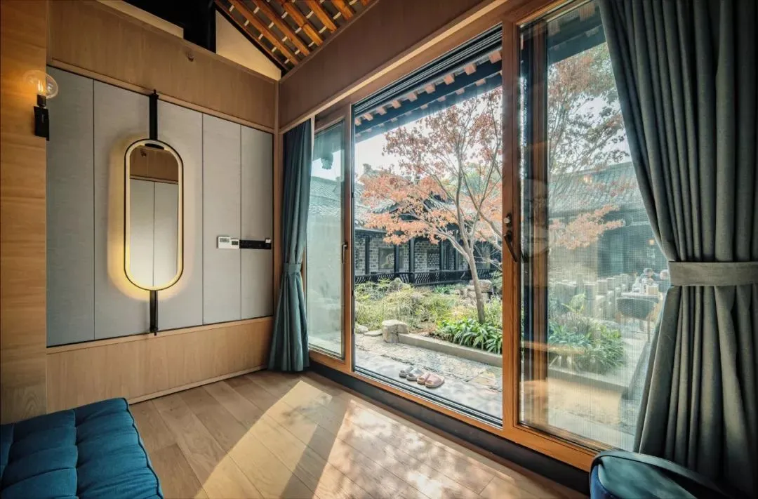 Modern luxury living room with a wooden floor and large windows overlooking a courtyard.