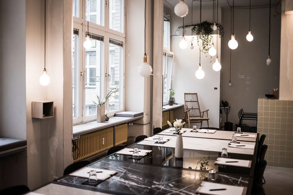 A modern office space with white marble tables and pendant lights.