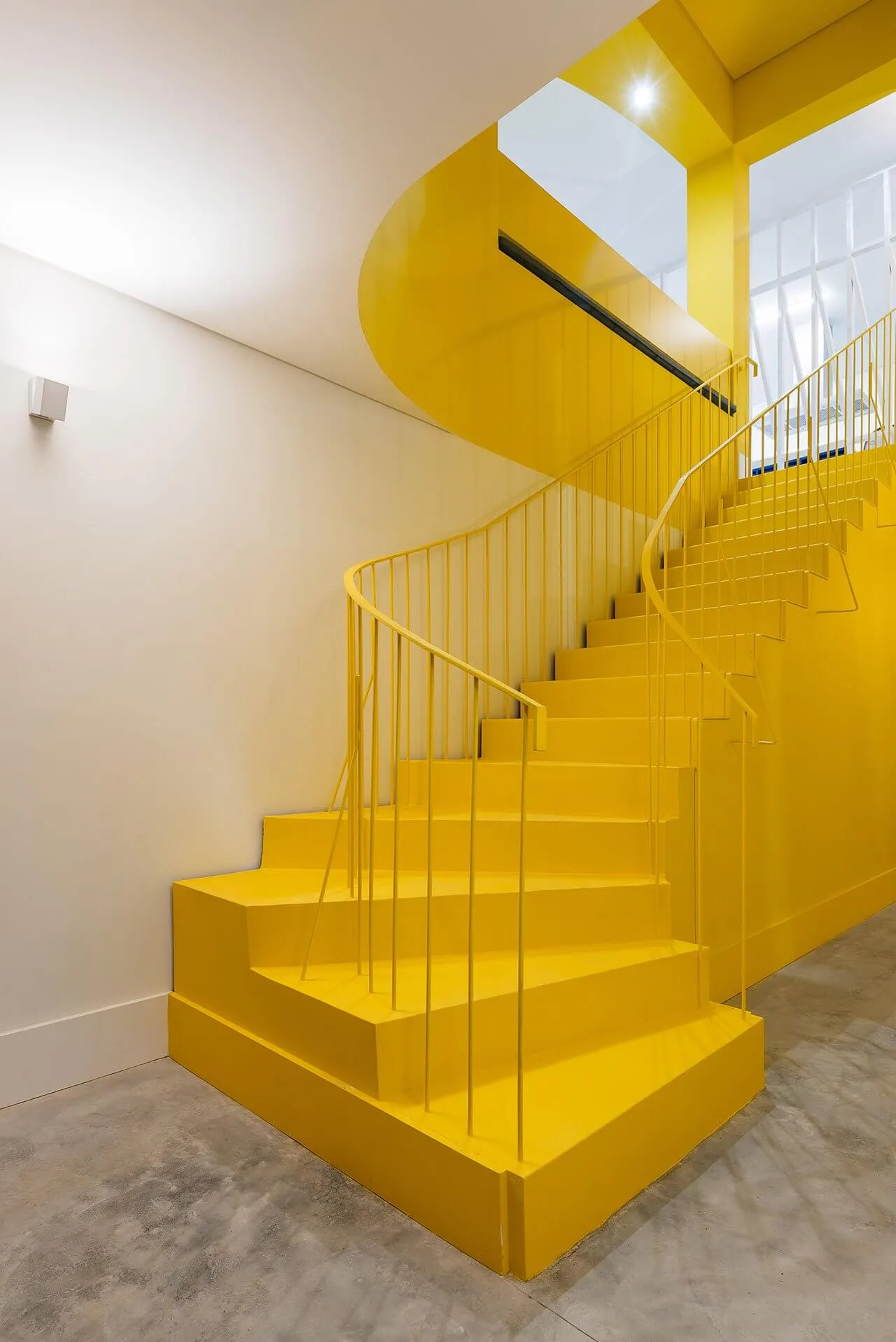 Modern interior with a bright yellow staircase painted with concrete materials.