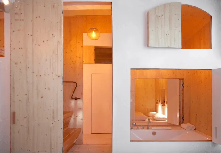 A modern bathroom featuring wooden walls and a wooden bathtub.