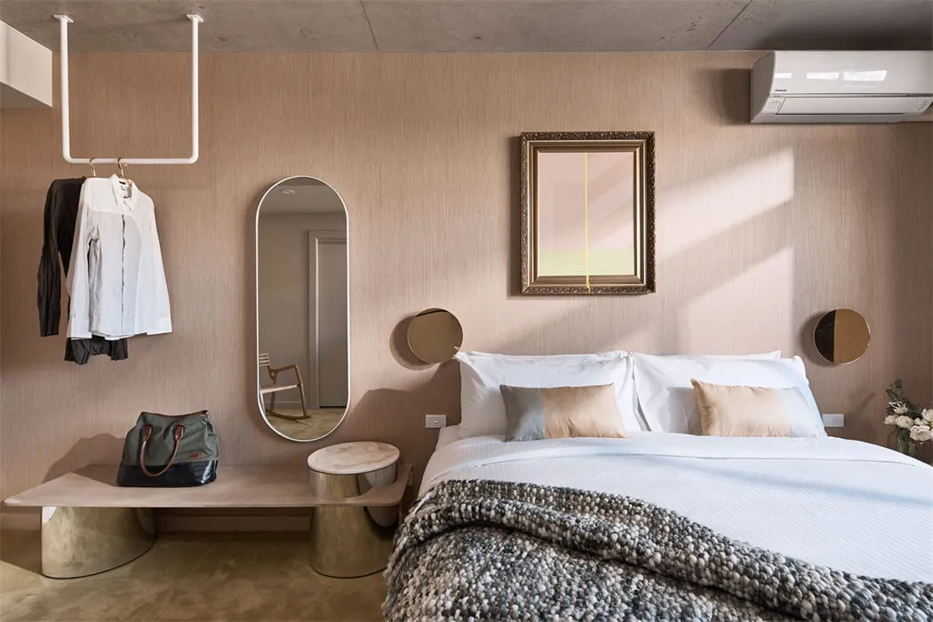 A modern bedroom featuring a bed with white bedding, a brown textured blanket, and mixed materials in the decor, including a