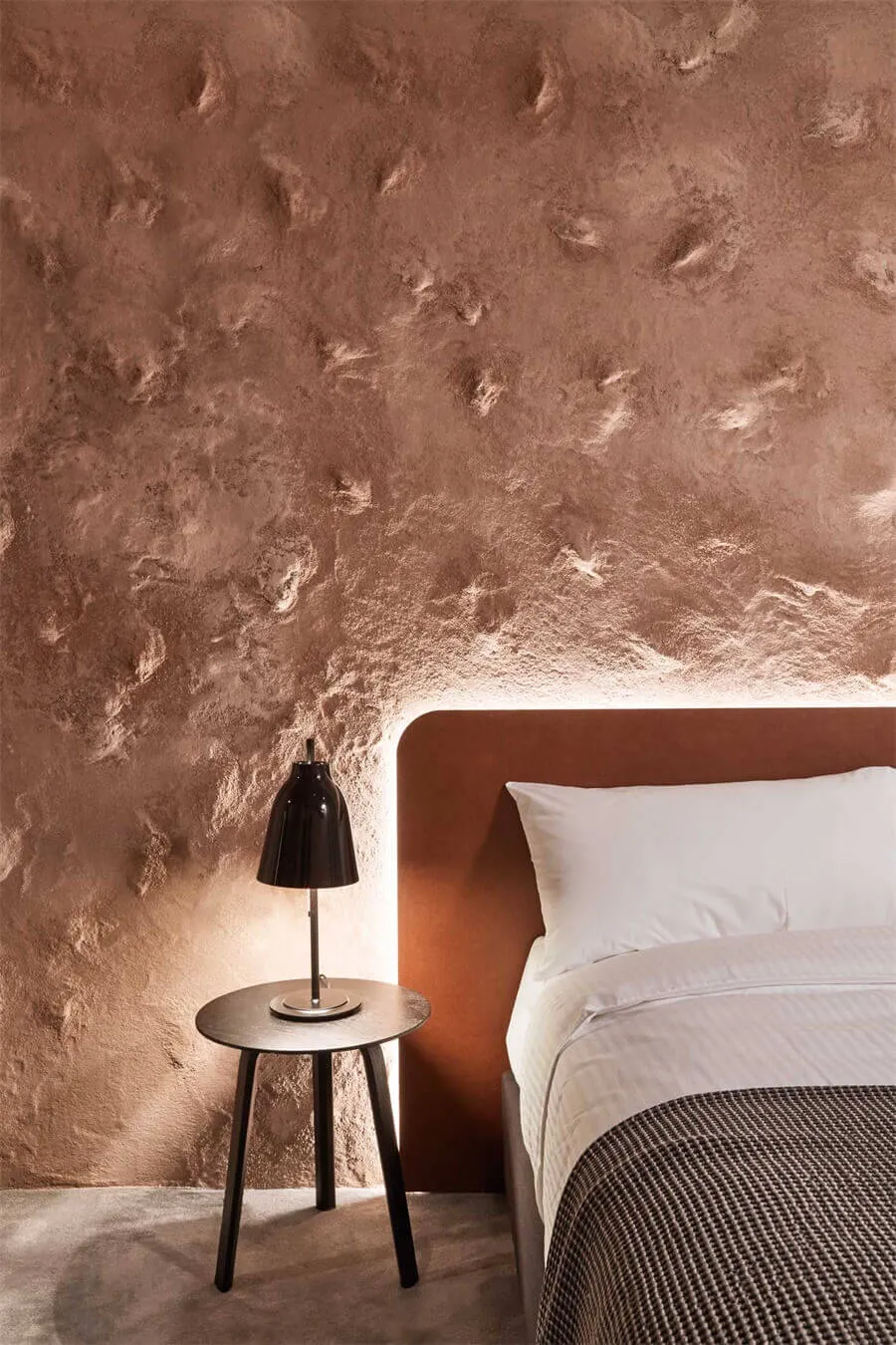A modern bedroom featuring a textured brown wall accent, with a cozy feel and minimalist decor.