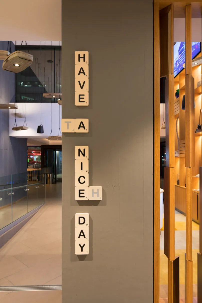 一面牆上掛著工業風木質字母拼板,拼出「HAVE A NICE DAY」。
