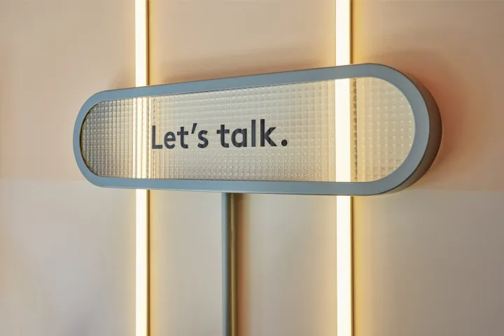 A minimalist sign featuring metallic-surfaced text that reads 'Let’s talk.'