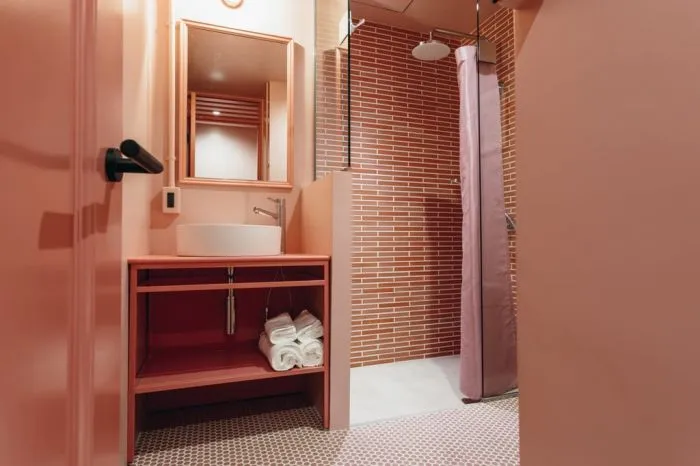 A modern bathroom featuring pink brick tiles and a pink vanity.