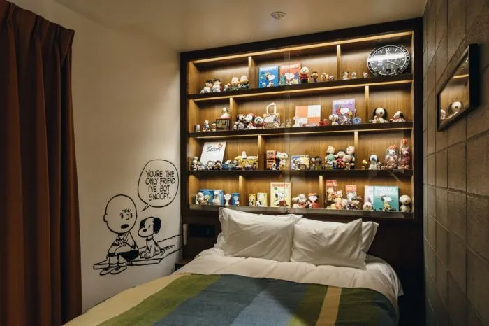 A modern bedroom with wooden shelves featuring Snoopy and Charlie Brown memorabilia.