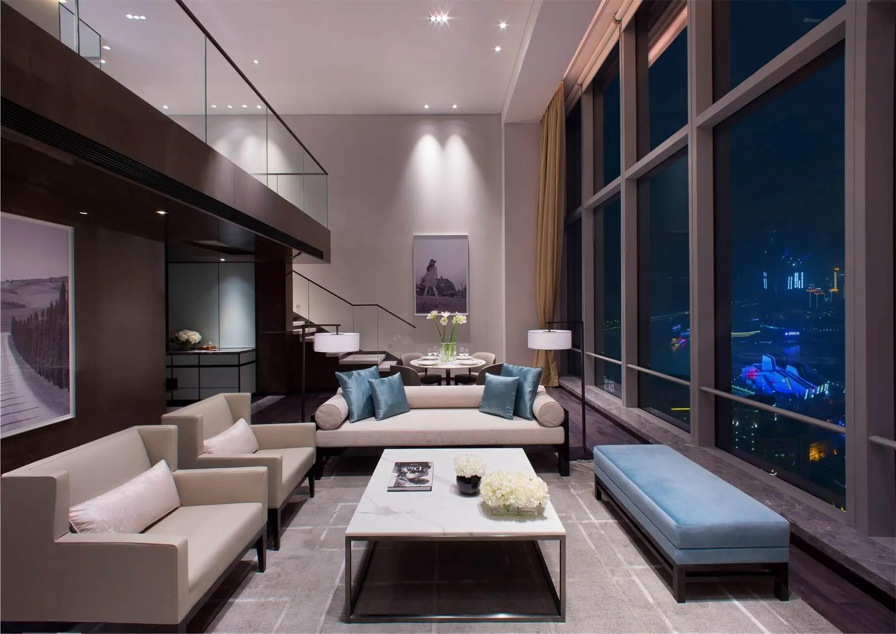 A modern living room with fabric seating, glass walls, and metal accents.