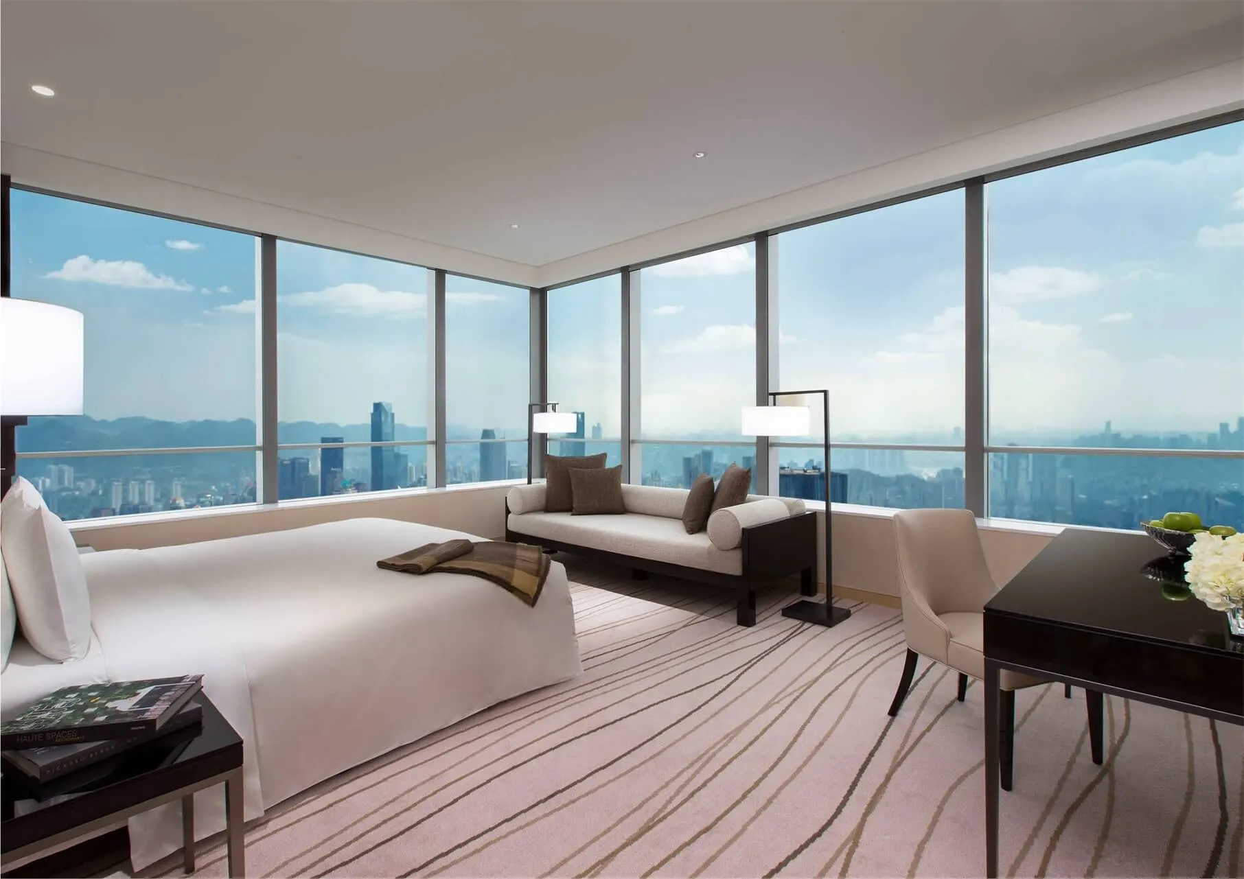 A modern residential interior featuring a bedroom with a large window overlooking a cityscape.