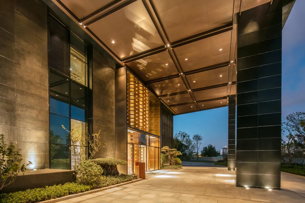 A modern hotel entrance with metallic walls and large glass windows.
