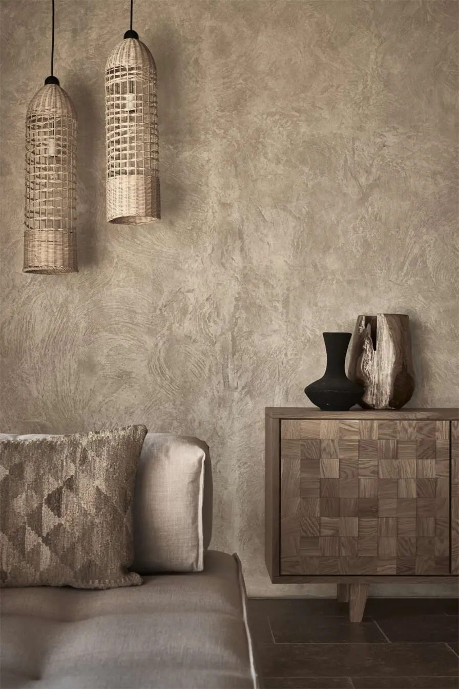 Modern living room featuring textured concrete walls and a wooden cabinet with a mix of baskets and vases.