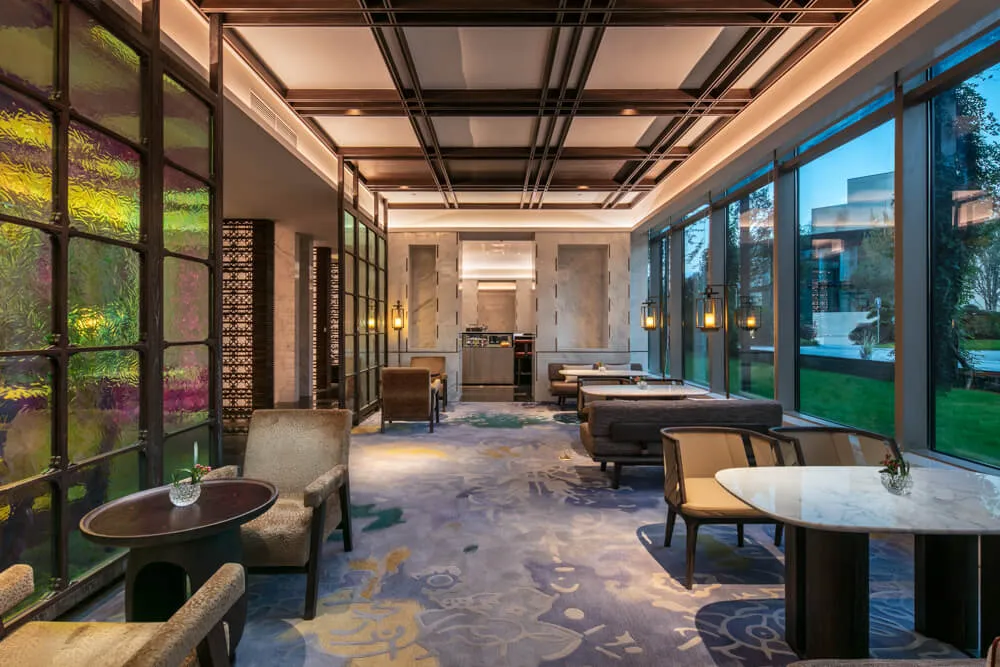 Modern, luxurious restaurant interior with elegant seating, marble tables, and stained glass windows.