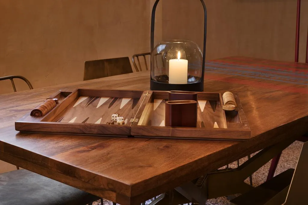 A wooden gameboard with dice and candles on a wooden table.