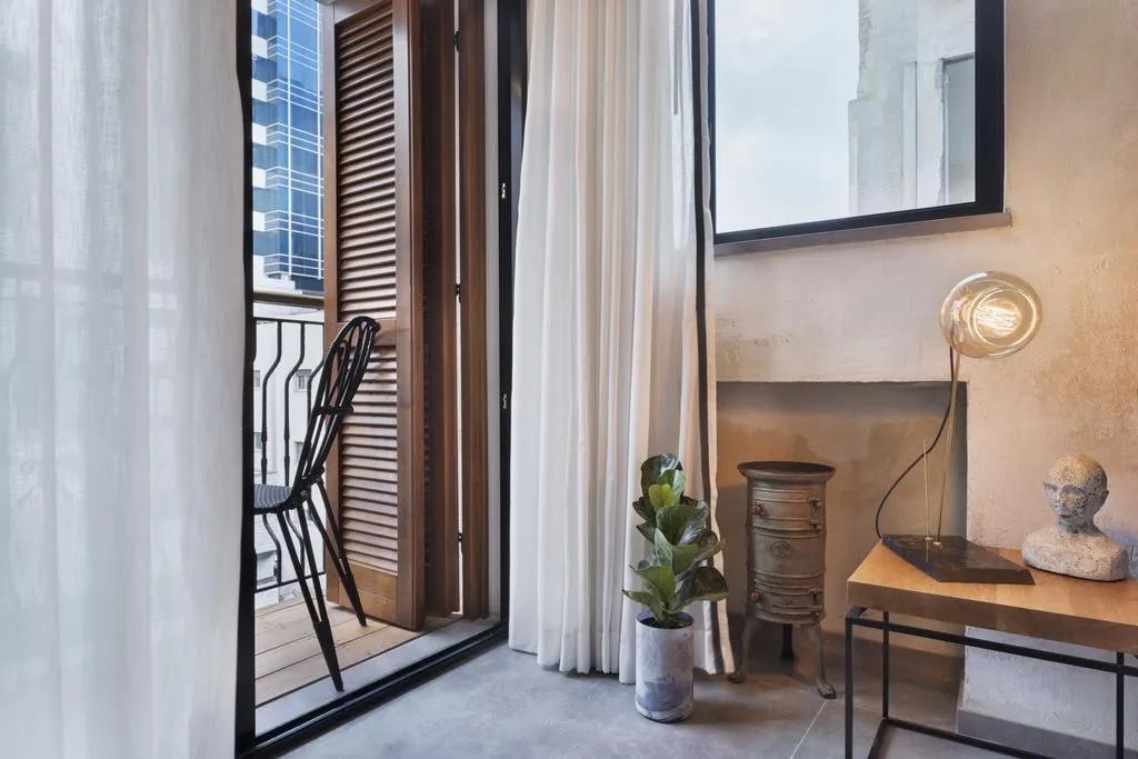 Industrial-style sitting area with a chair, potted plant, and a lit table lamp.