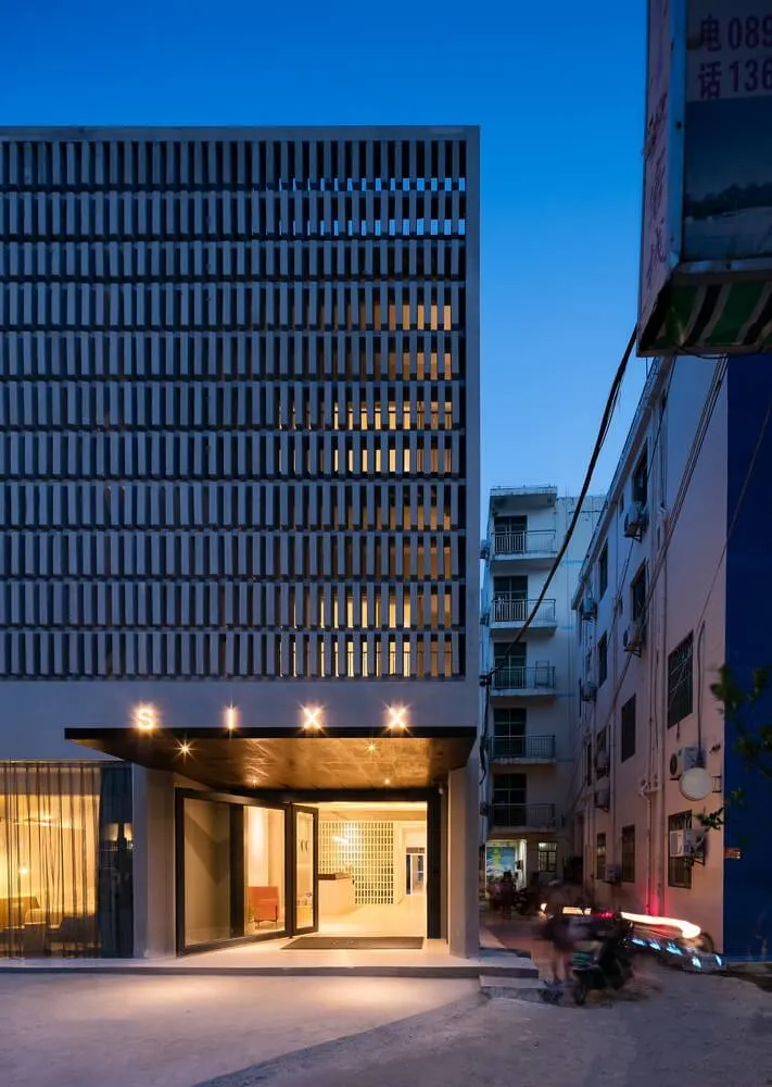 A modern glass exterior of a hotel building at dusk.