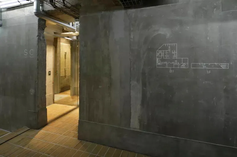 Concrete walls and floor in an industrial-style lobby with a blueprint drawing on the wall.