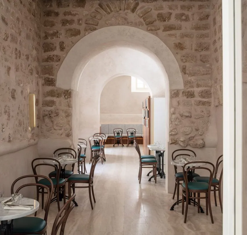 Modern minimalist cafe interior featuring stone walls and concrete flooring.