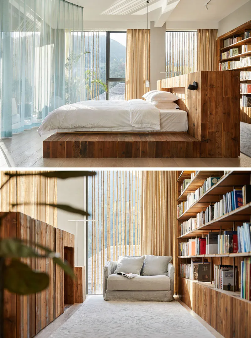 Modern bedroom featuring a wooden platform bed with white bedding, large windows, and a bookshelf.