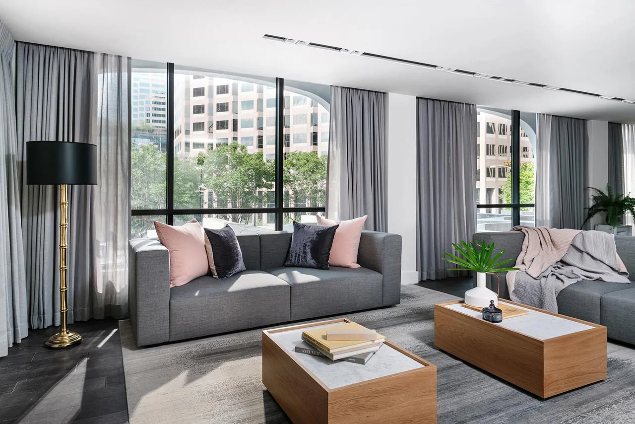 Modern living room with grey couches, large windows, and grey curtains