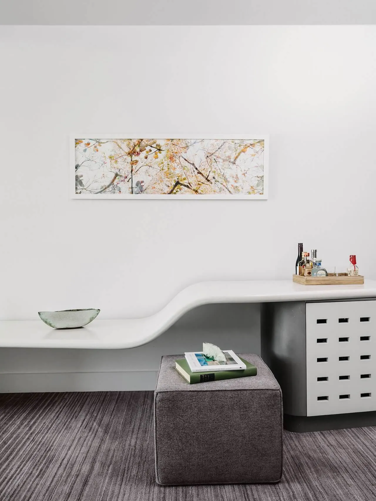 A modern minimalist living room with concrete furniture and a white geometric console table with a bowl on top.