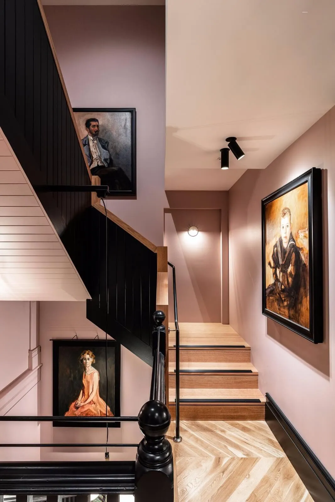 Modern staircase featuring black railings, wooden steps, and framed artworks on the walls.