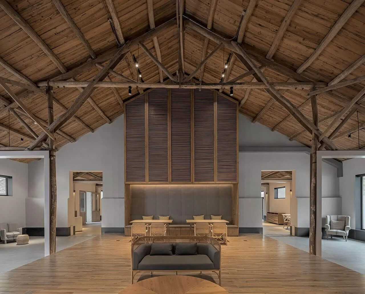 Industrially styled lobby with wooden furniture and walls, featuring high ceilings and exposed beams.
