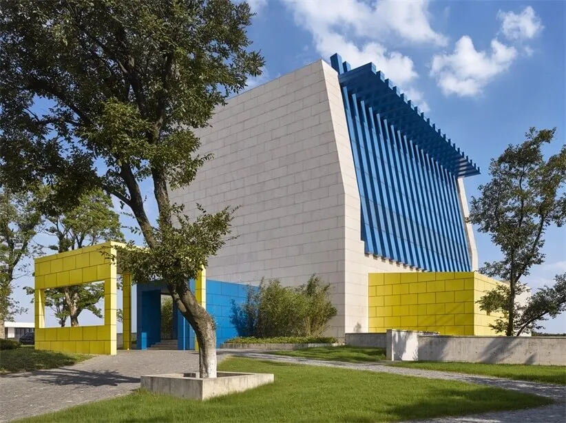 A modern building with a glass facade, yellow accents, and a white exterior.
