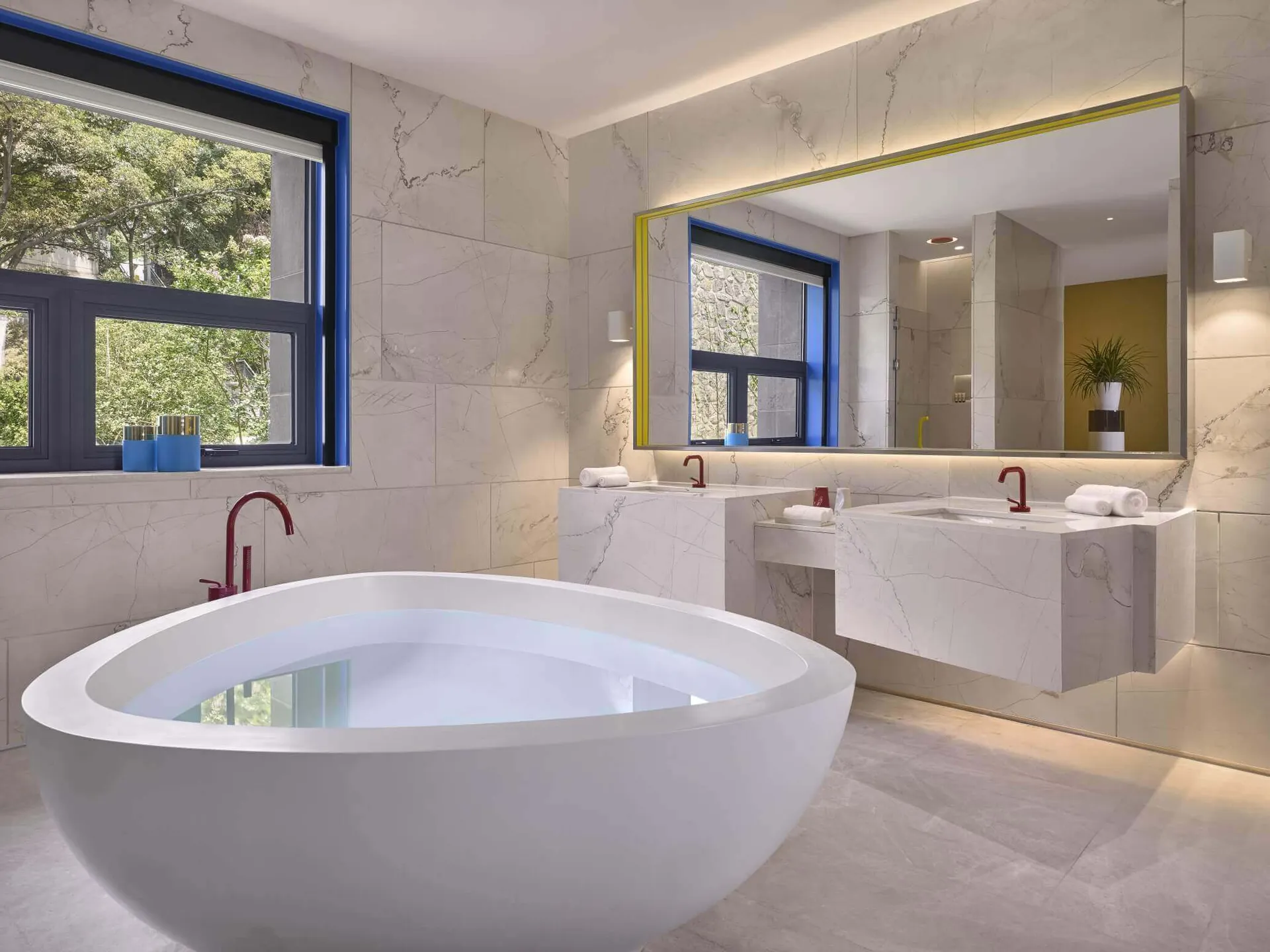Modern marble bathroom with a round tub and two sinks.