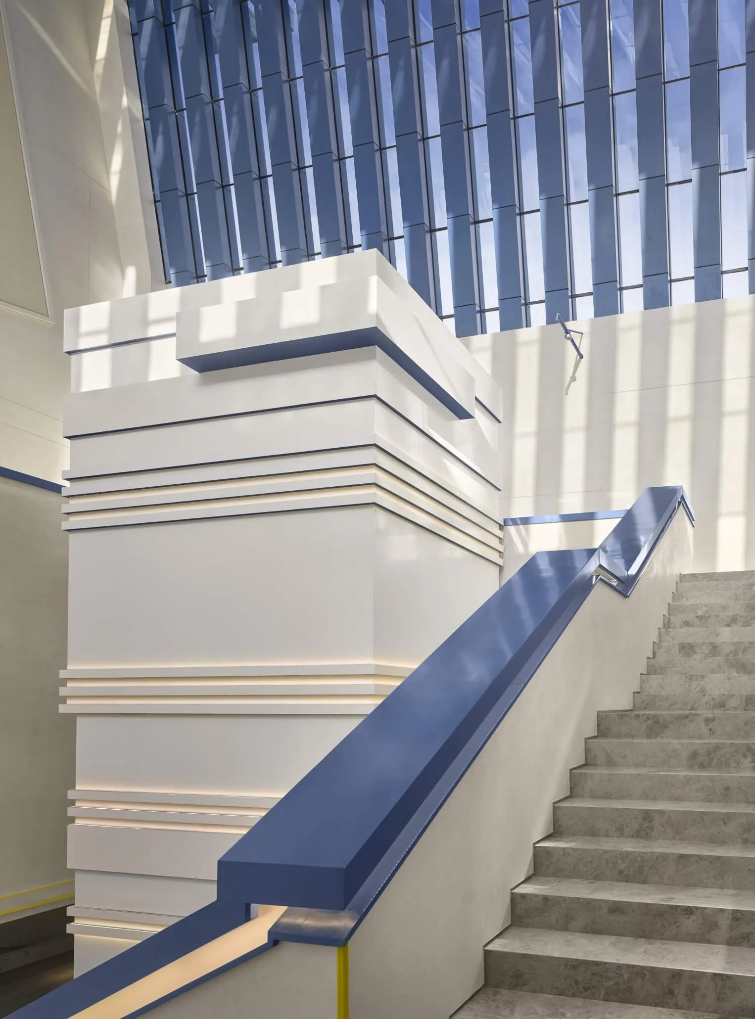 A modern staircase with white concrete steps and a blue acrylic handrail.
