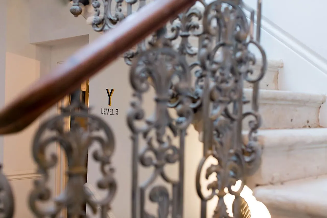 Close-up of ornate wrought iron staircase railing and wooden banister.
