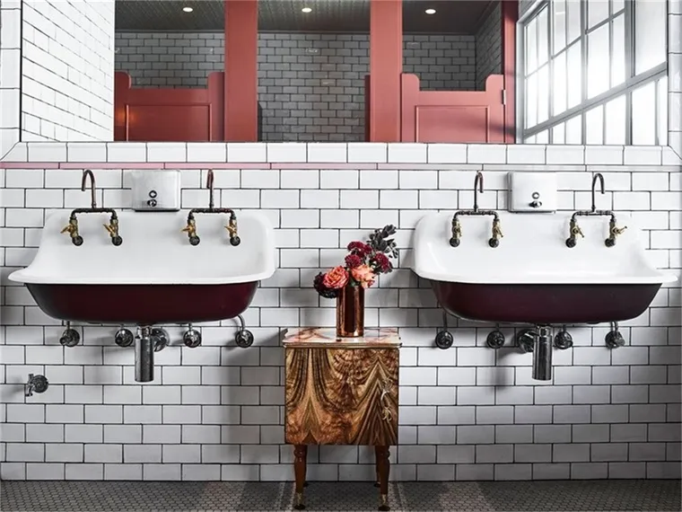 Industrial-style bathroom with concrete sinks and art deco design elements.