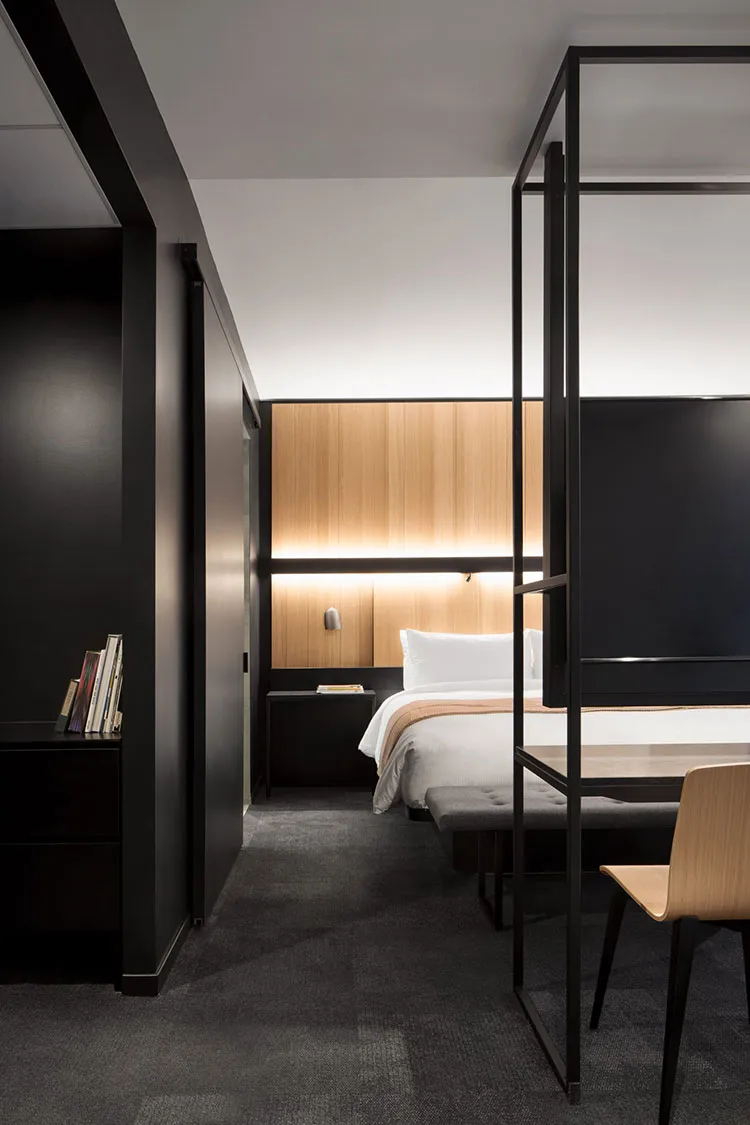 Modern minimalist bedroom with black and white color scheme, wooden accents, and steel furniture.