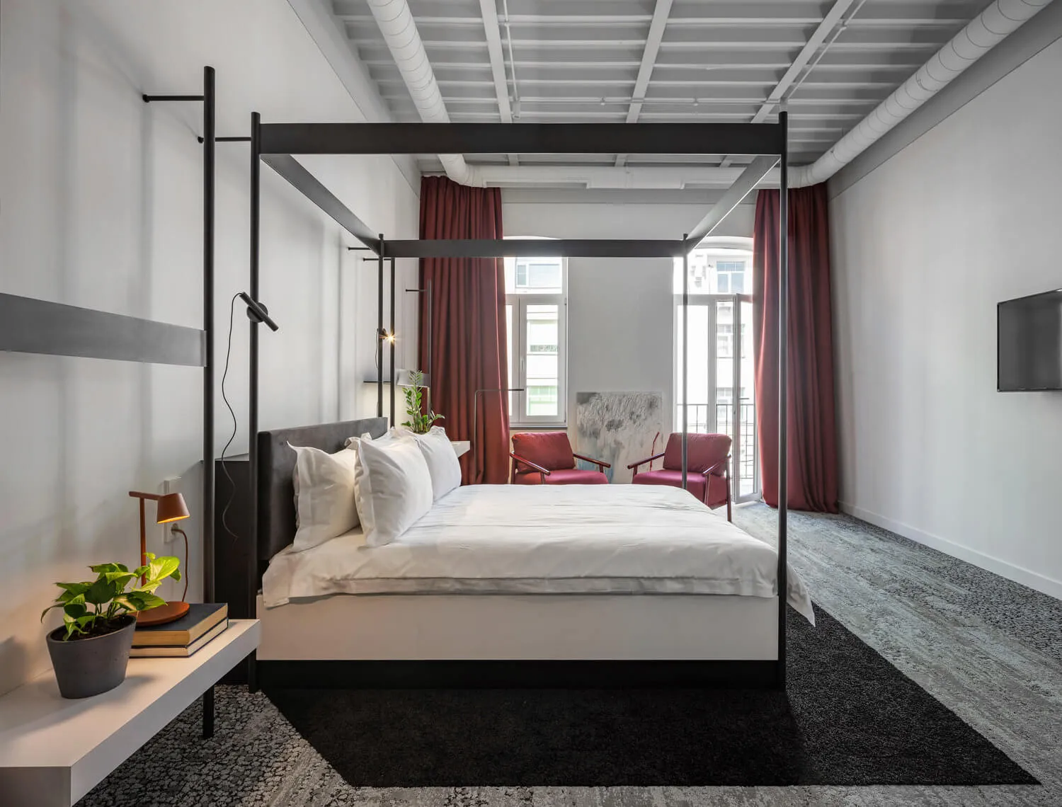 Modern bedroom with a black-framed bed, white bedding, and red curtains.