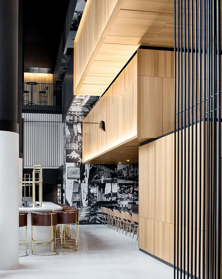 Modern cafeteria interior with wooden panels, metal railings, and concrete floors.