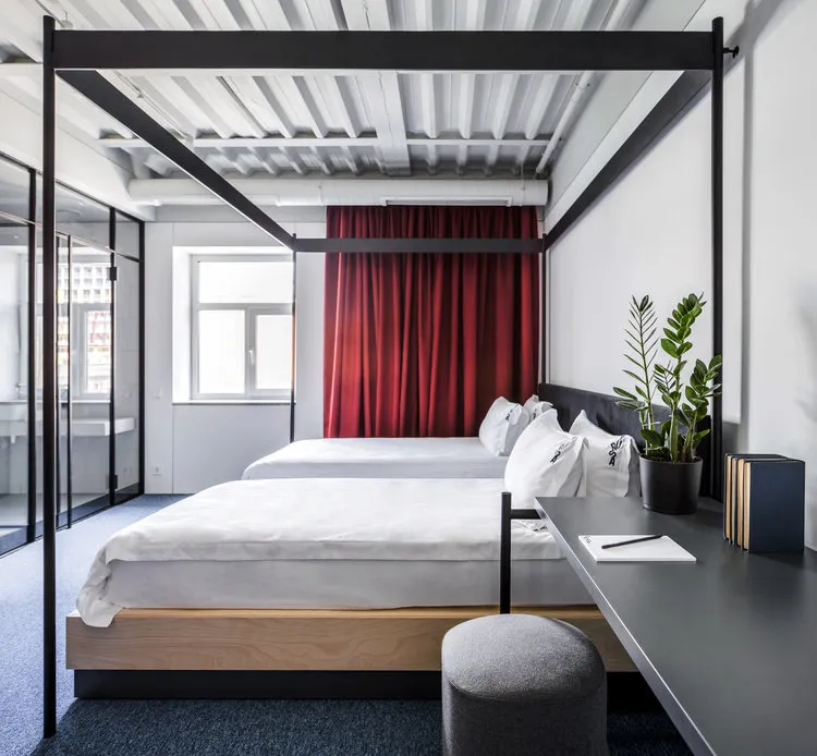 A modern living room with minimalist design, featuring wooden furniture, white walls, and a white bed with metal frame.