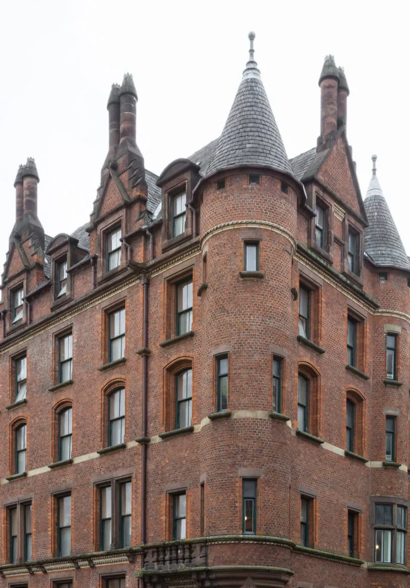 A brick building with intricate architectural details, featuring conical roof structures and large windows.