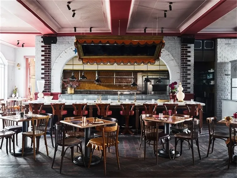 Industrial-style restaurant interior with wooden tables, brick walls, and metal accents