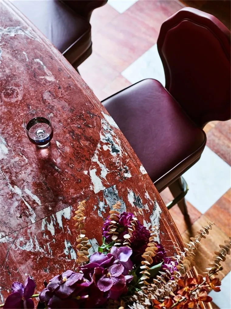 Industrial restaurant interior with dark-red marble countertop and purple flowers.