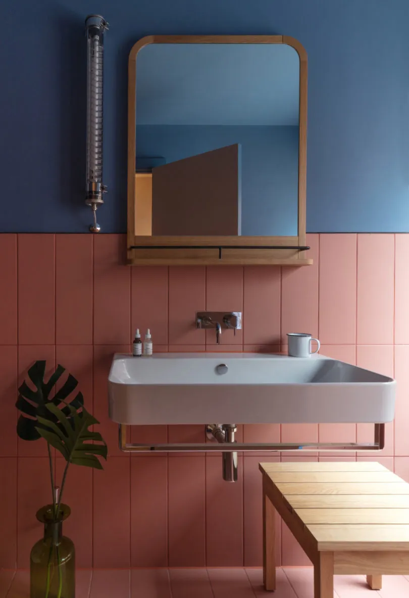 Modern bathroom with ceramic tiles, a floating white sink, and a wooden mirror frame.
