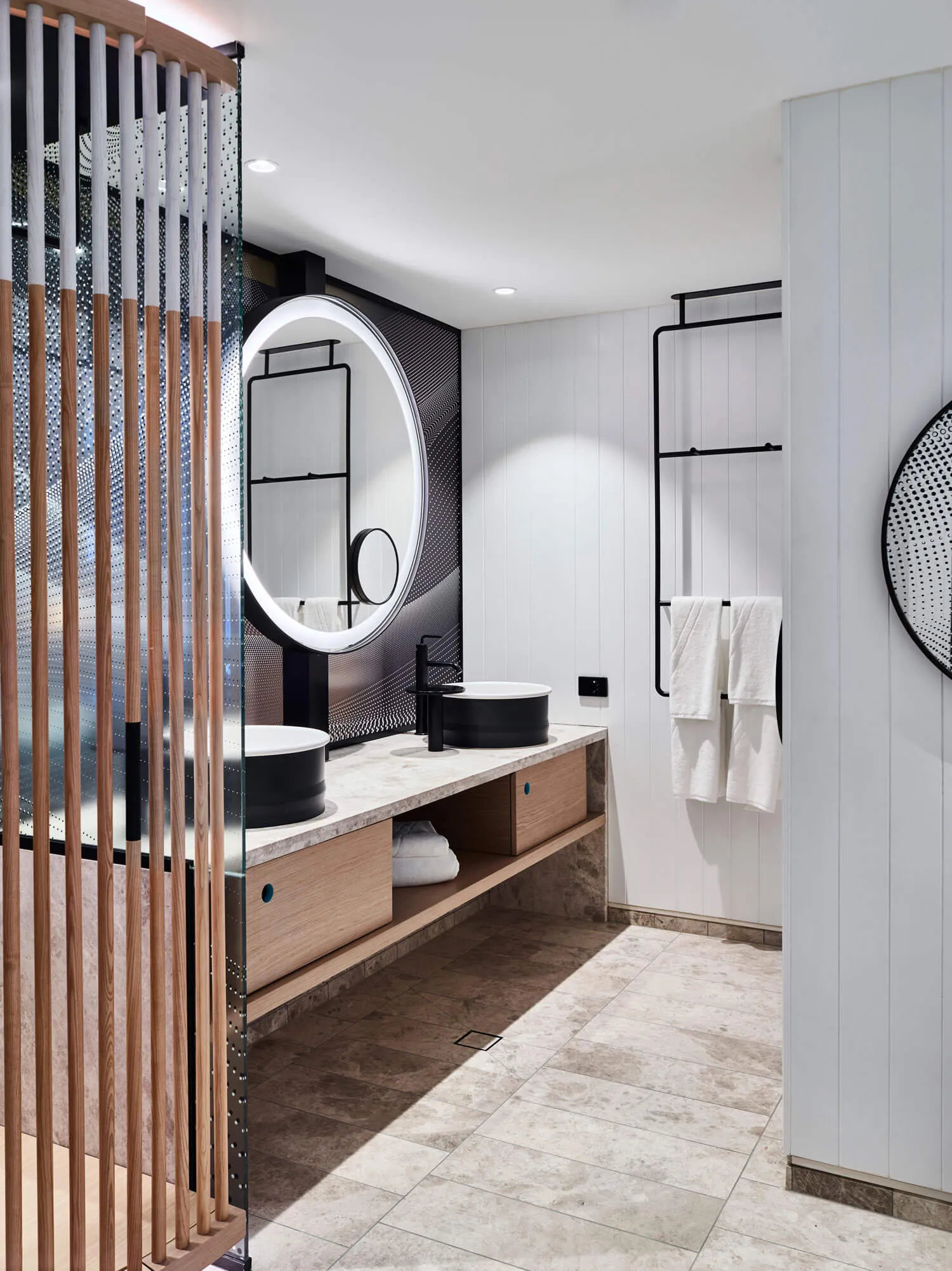 Modern bathroom featuring marble countertops, wooden cabinets, and metal hardware.