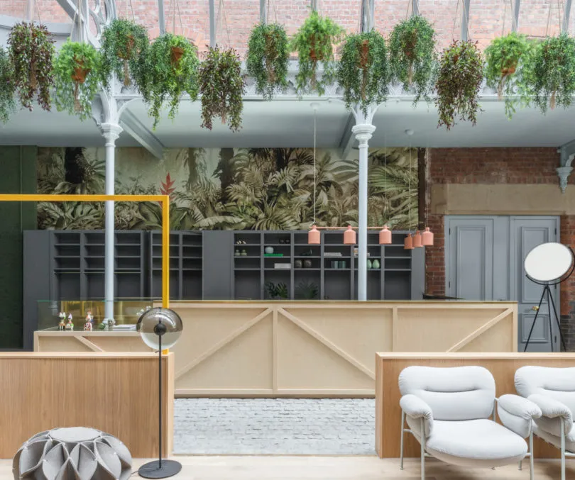 Modern commercial space featuring industrial design elements such as exposed concrete, wooden furnishings, and hanging green