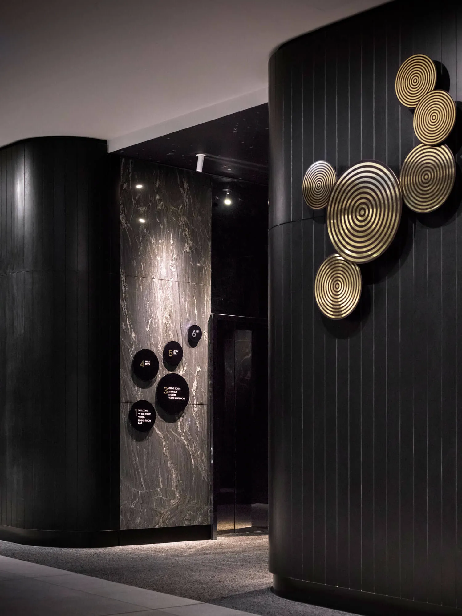 A modern hotel lobby featuring marble and black wood elements.